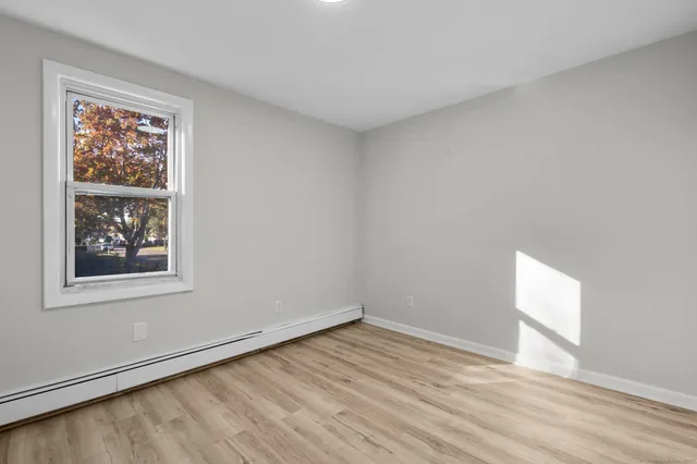 an empty room with wooden floor and white walls