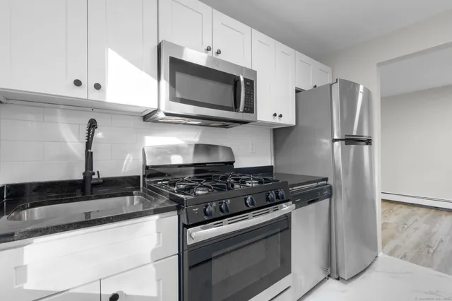 a kitchen with granite countertop white cabinets stainless steel appliances and a sink