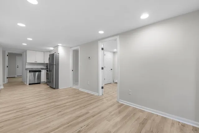 a view of a hallway with wooden floor and a kitchen
