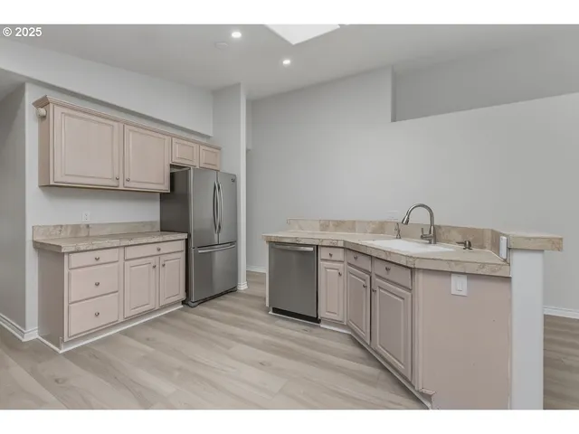 a kitchen with a sink cabinets stainless steel appliances and a window