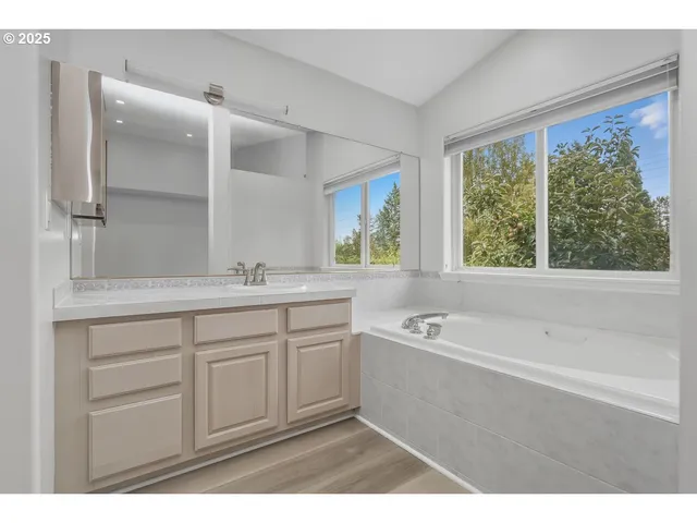 a spacious bathroom with a tub sink and mirror