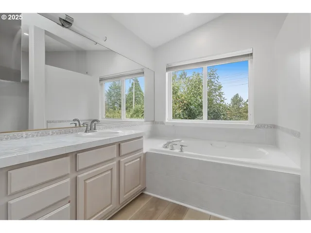 a bathroom with a tub a sink and a window
