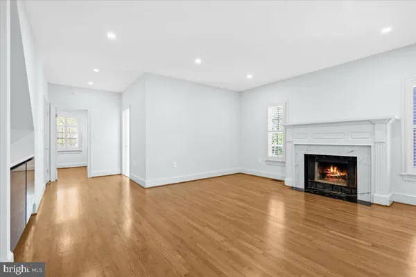 a view of an empty room with wooden floor fireplace and a window