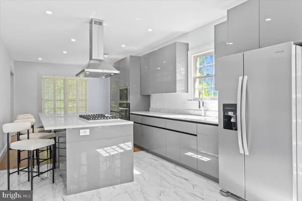 a kitchen with kitchen island a refrigerator a stove a sink and chairs