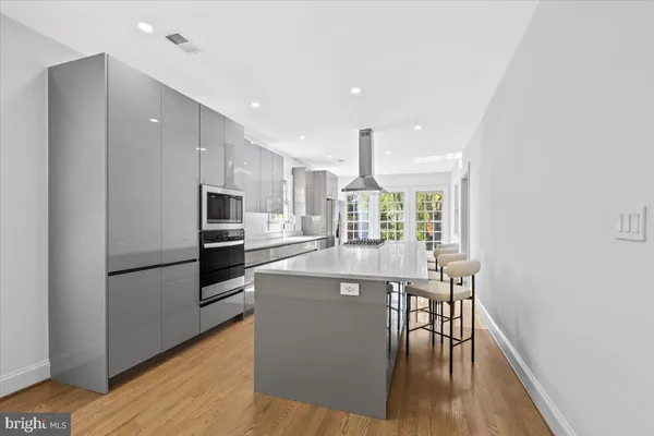 a kitchen with stainless steel appliances a dining table chairs and wooden floor