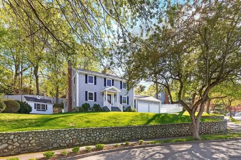 a front view of a house with a garden and trees
