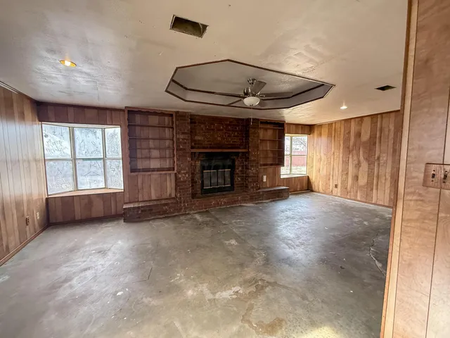an empty room with windows and fireplace
