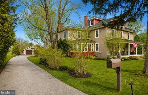 a front view of a house with garden and trees