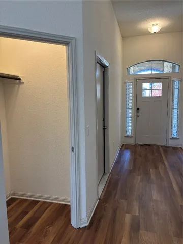 a view of a hallway with wooden floor and closet