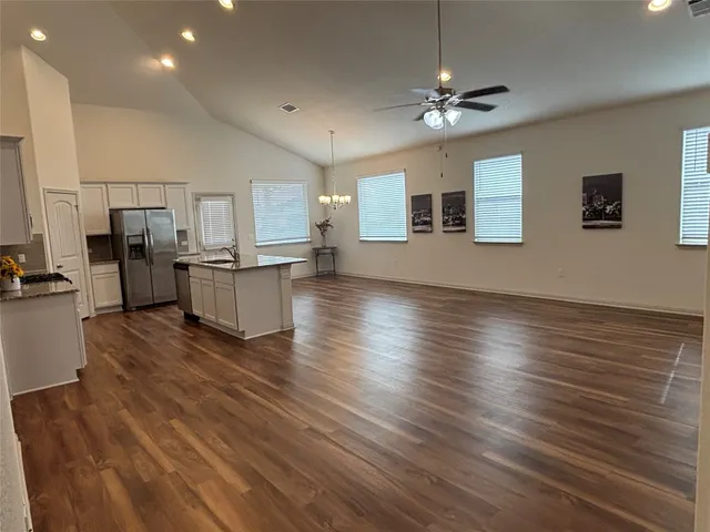 a view of a livingroom with furniture wooden floor a ceiling fan and windows