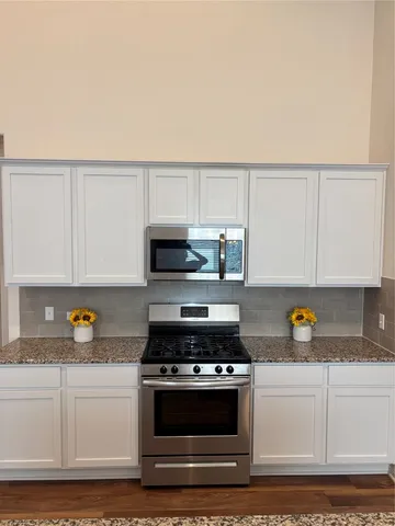 a kitchen with stainless steel appliances granite countertop a stove a sink and a white cabinets