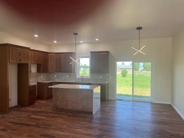 a kitchen with kitchen island a sink wooden floor and a refrigerator