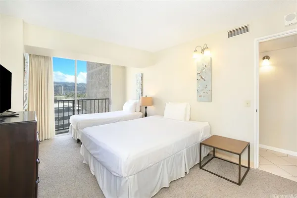 a spacious bedroom with a bed and a flat tv screen next to a window