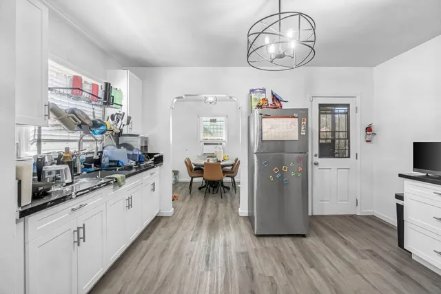 a kitchen with stainless steel appliances granite countertop a refrigerator a stove oven and white cabinets with wooden floor