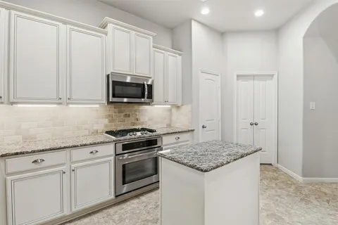 a kitchen with granite countertop a sink stove and microwave