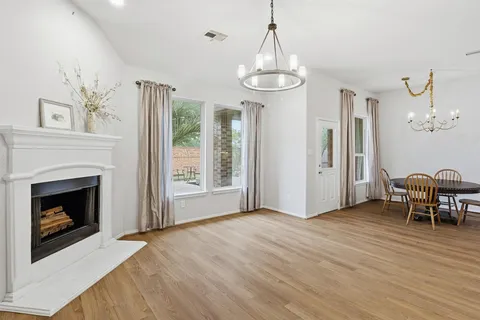 a view of a livingroom with a fireplace wooden floor and chandelier