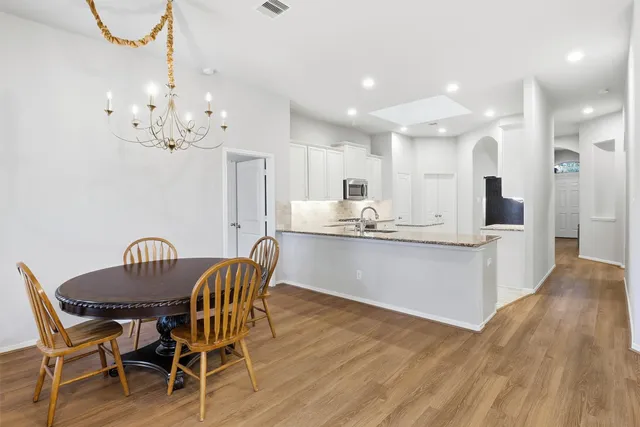 a kitchen with kitchen island granite countertop a table chairs a sink dishwasher refrigerator and cabinets