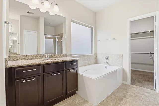 a bathroom with a tub a sink and mirror