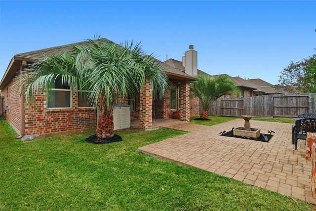 a view of a backyard with couches plants and large trees
