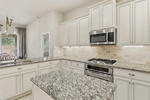 a kitchen with granite countertop a sink stove and microwave