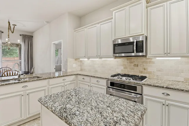 a kitchen with granite countertop a sink stove and microwave
