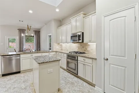 a kitchen with kitchen island granite countertop appliances cabinets and a sink