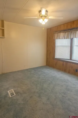 en empty room with windows and chandelier fan