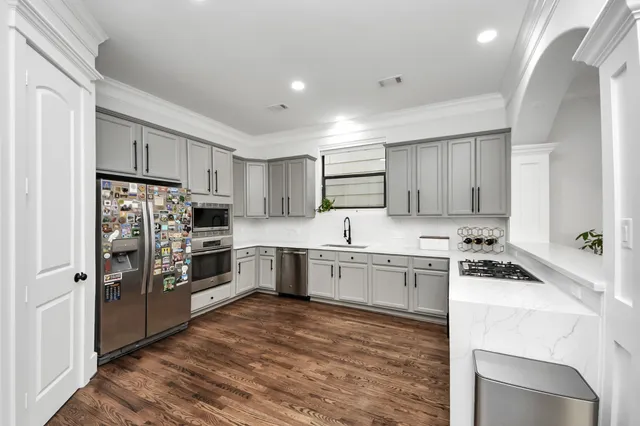 a kitchen with a sink white cabinets and stainless steel appliances