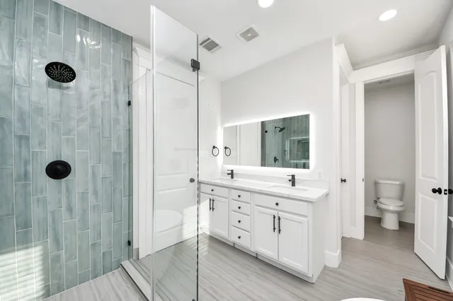 a spacious bathroom with a double vanity sink a mirror and a toilet