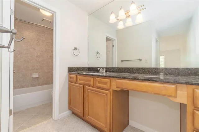 a bathroom with a granite countertop sink a mirror and a bathtub