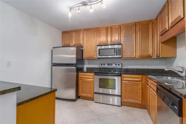 a kitchen with stainless steel appliances granite countertop a stove a refrigerator and a stove top oven