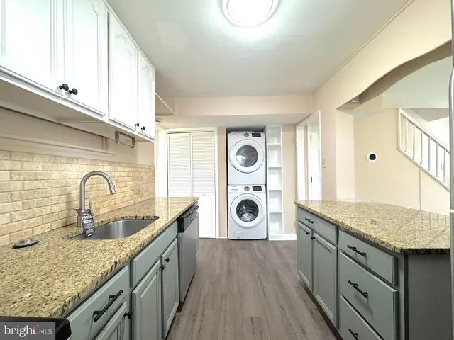 a kitchen with granite countertop a sink a stove and washer with dryer