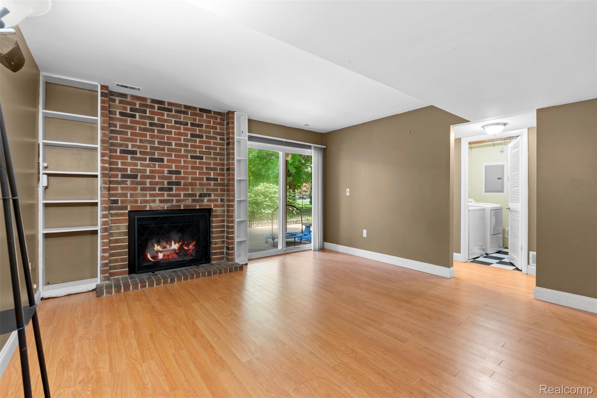 22530 Sheridan Road Novi, MI 48375 - Photo 19 of 50 Unfurnished living room featuring light wood-style floors, a brick fireplace, washing machine and dryer, and electric panel