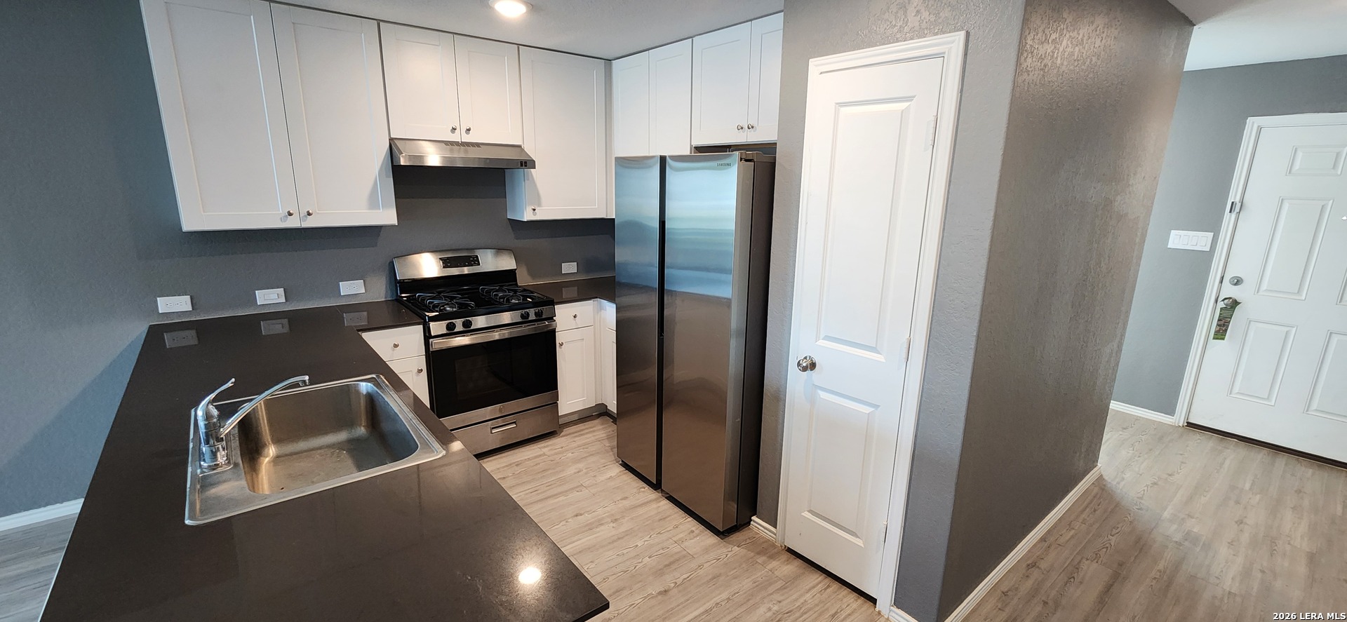 6013 Companion Loop Bulverde, TX 78163 - Photo 2 of 37 a kitchen with stainless steel appliances granite countertop a refrigerator a stove and a sink with wooden floor