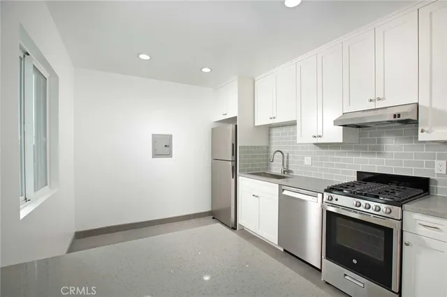 a kitchen with stainless steel appliances granite countertop white cabinets and a stove top oven