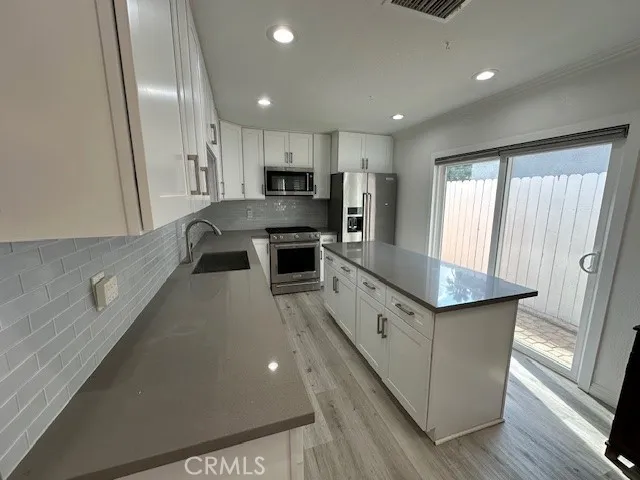 a large kitchen with stainless steel appliances a large counter top a stove a sink and a refrigerator