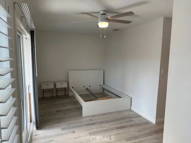 an empty room with wooden floor fan and windows