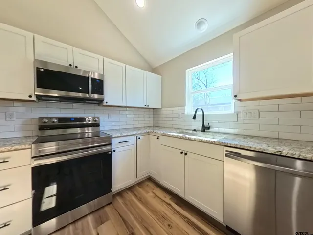 a kitchen with stainless steel appliances granite countertop a sink and a stove top oven