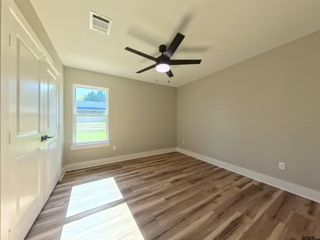 a view of a room with a ceiling fan and wooden floor