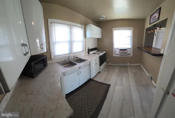 a kitchen with granite countertop a refrigerator a sink dishwasher stove and white countertops with wooden floor