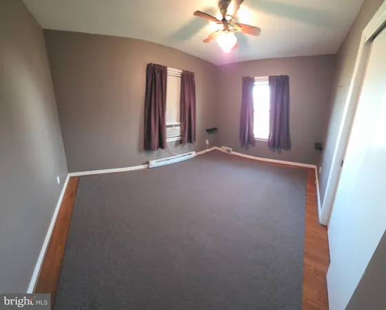 an empty room with windows and fan