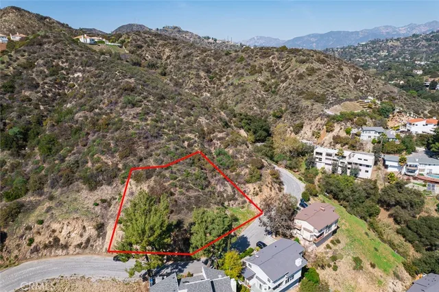 an aerial view of a houses with a street and mountains