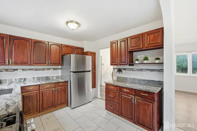 a kitchen with stainless steel appliances granite countertop a refrigerator and wooden cabinets