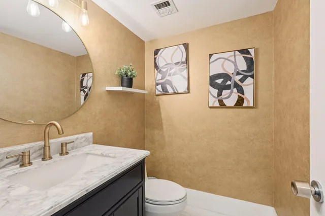 a bathroom with a granite countertop sink mirror vanity and toilet