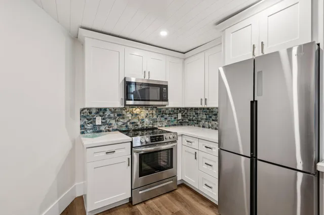 a kitchen with white cabinets and stainless steel appliances