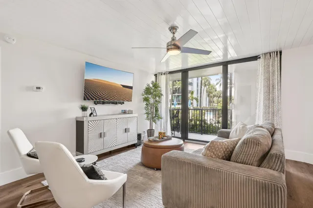 a living room with furniture a flat screen tv and a floor to ceiling window