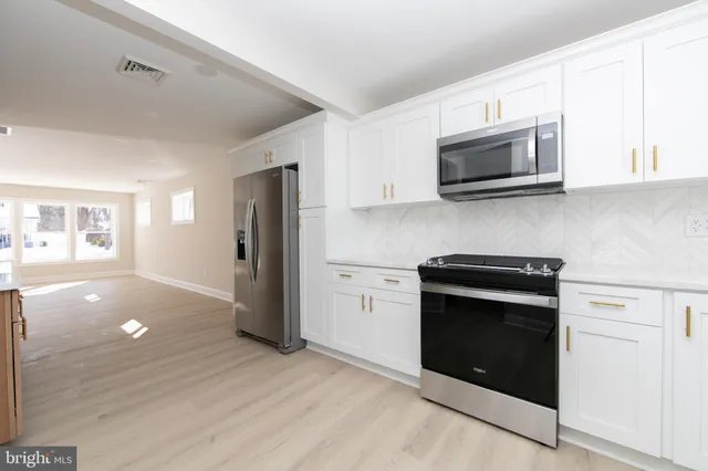 a kitchen with stainless steel appliances white cabinets and stove top oven