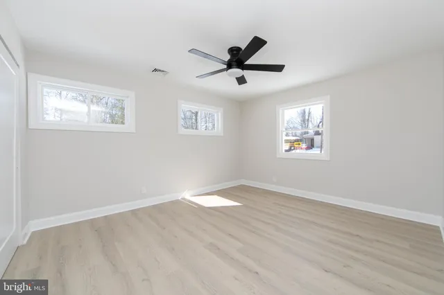 a view of an empty room with a window and wooden floor
