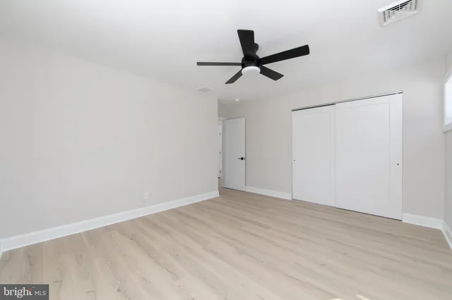 a view of a big room with wooden floor closet ceiling fan and window