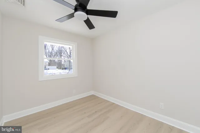 an empty room with a window and a fan